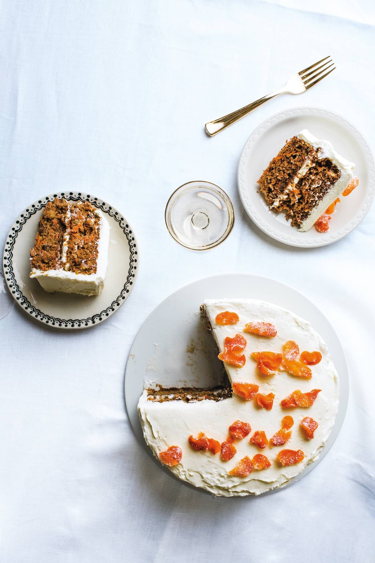 Carrot cake covered in cream cheese frosting, topped with sweet, chewy candied carrot coins