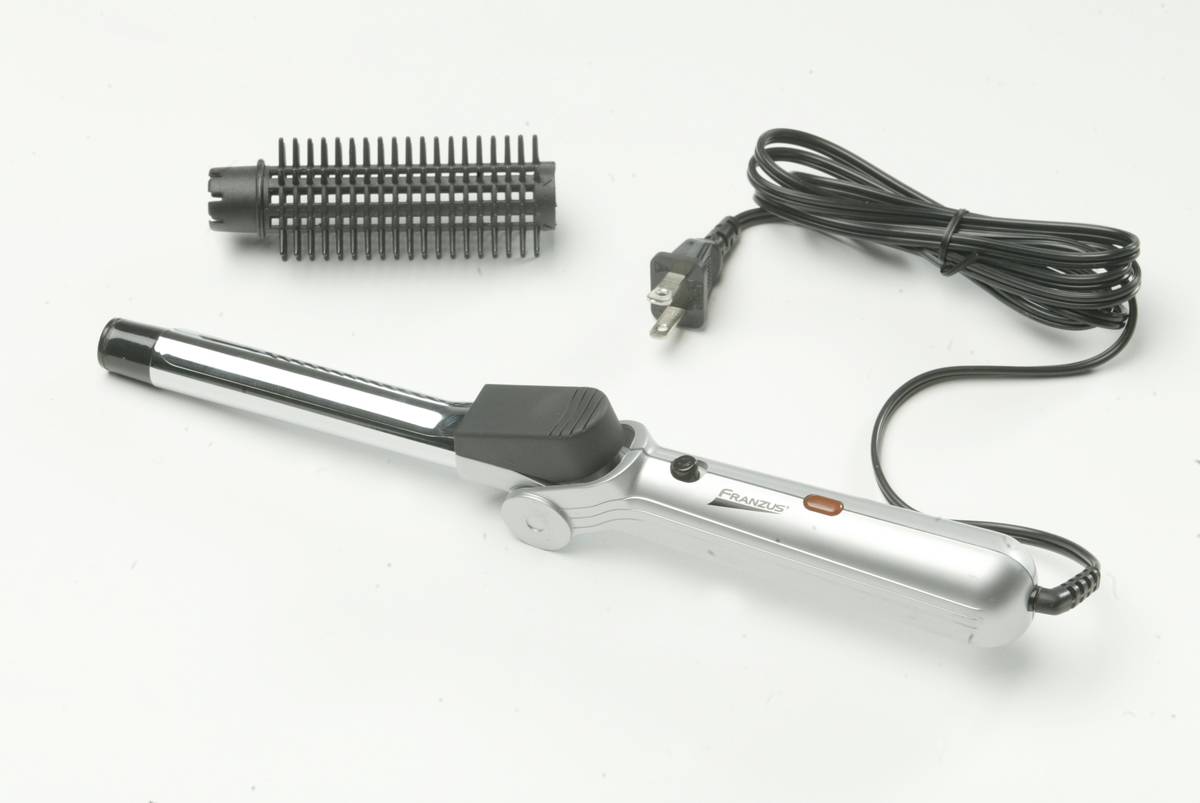 A curling iron and its cables lie against a white background