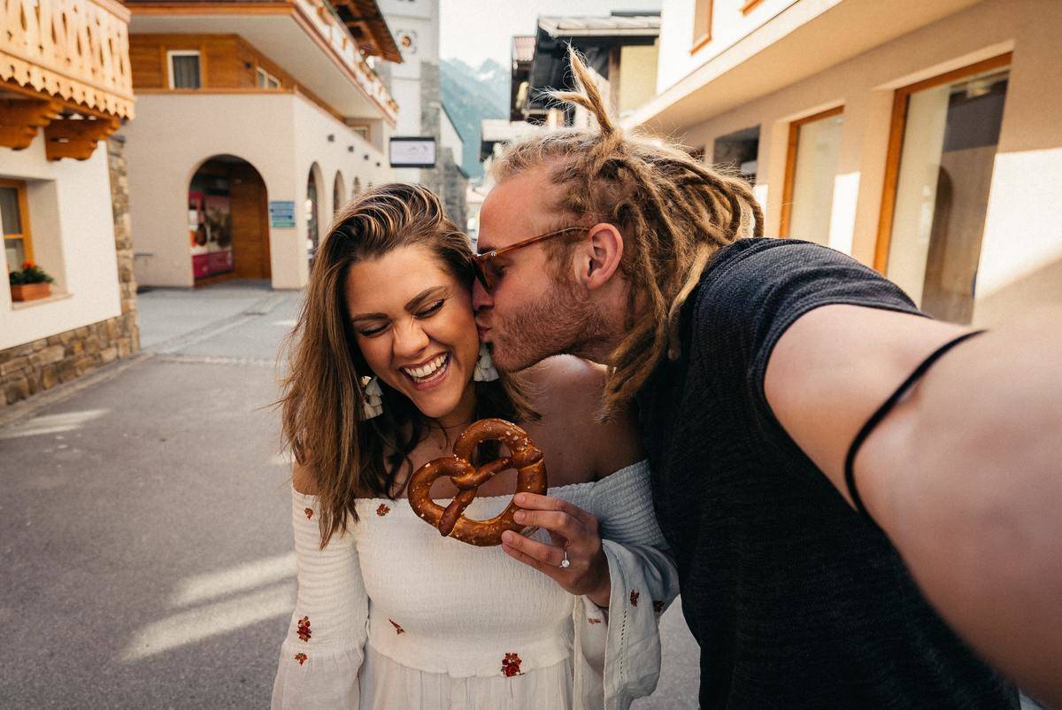 guy kissing a girl who is holding a pretzel