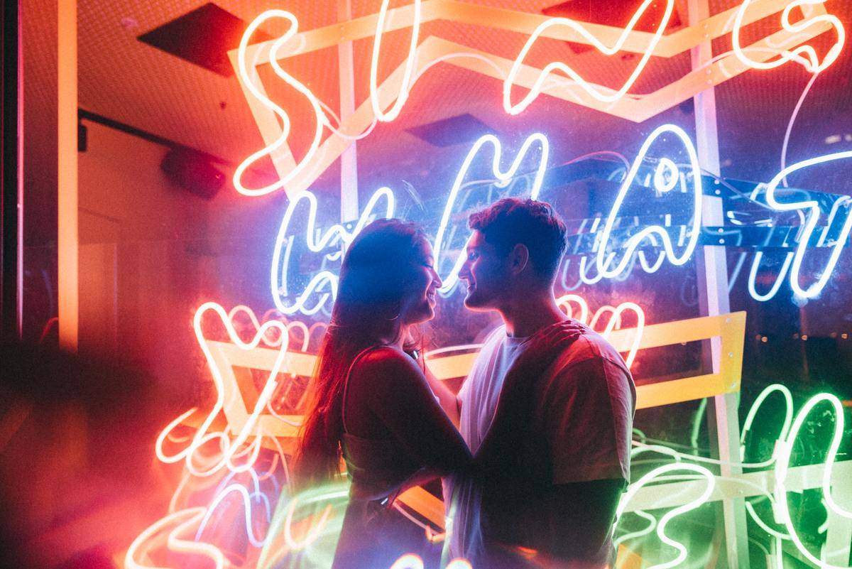 couple standing in front of neon lights