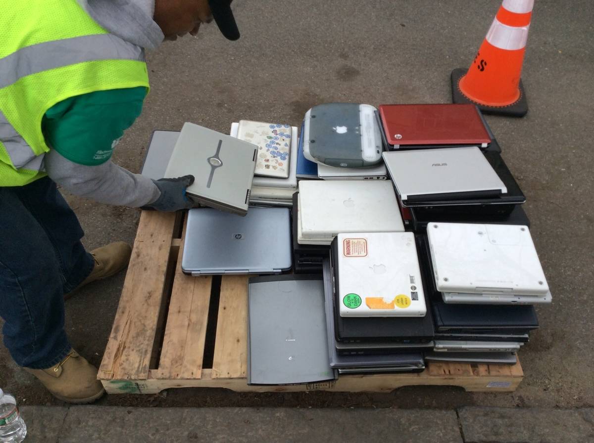 An employee sorts through recycled laptops.