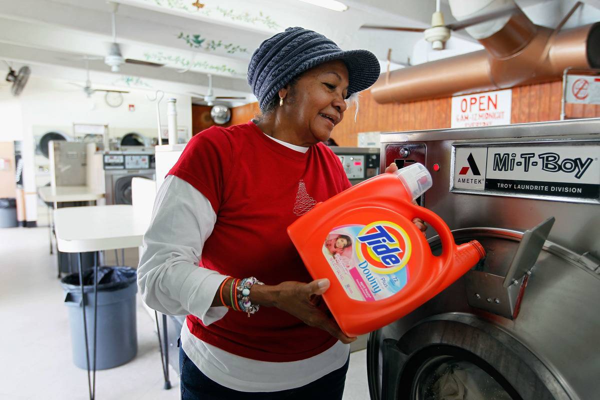 A woman pours laundry detergent into a washing