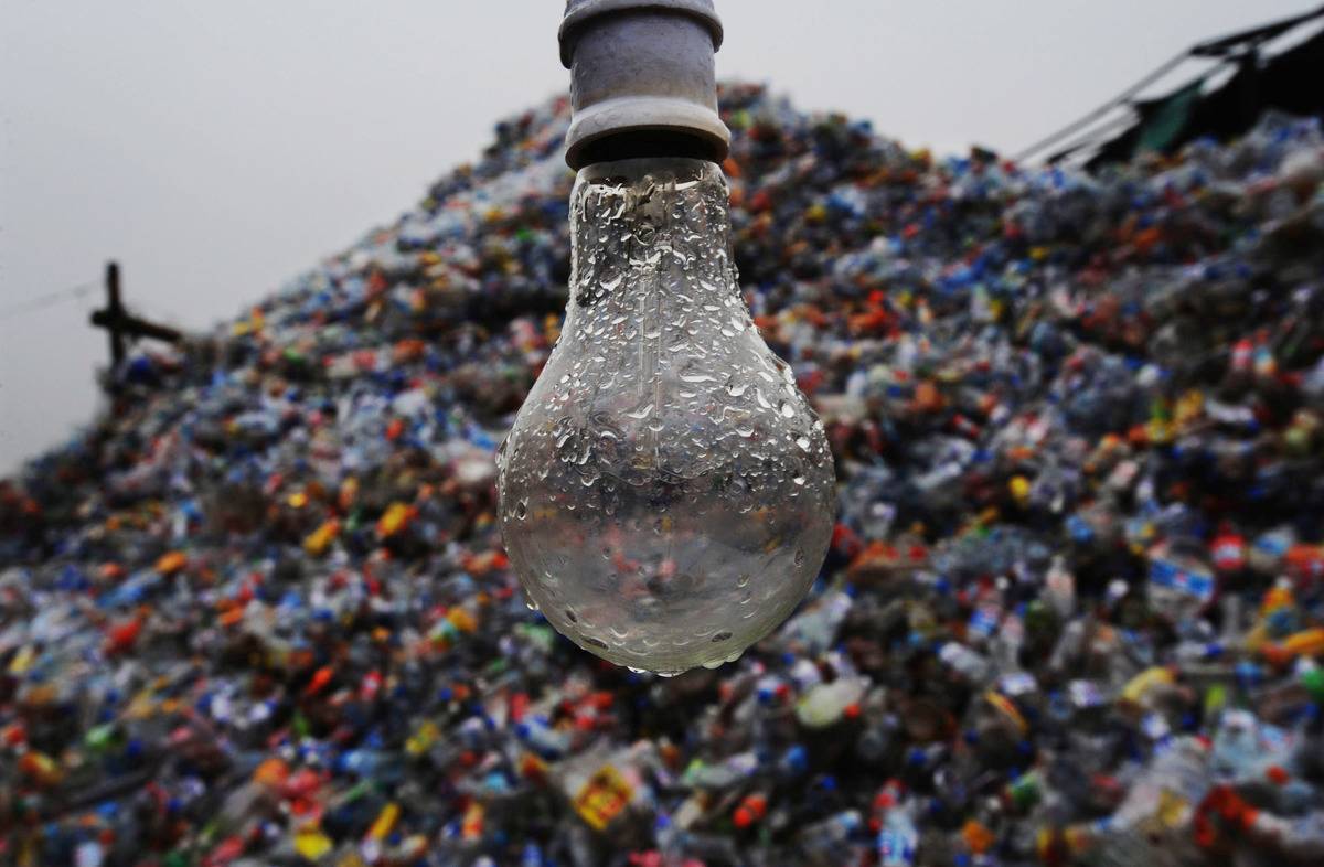A wet light bulb appears in front of a landfill.