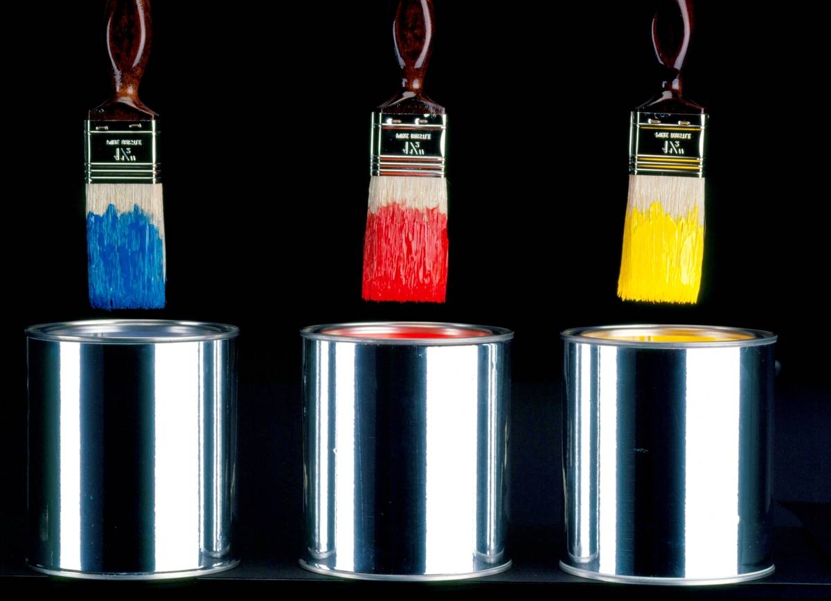 Paint brushes hover over tin cans.