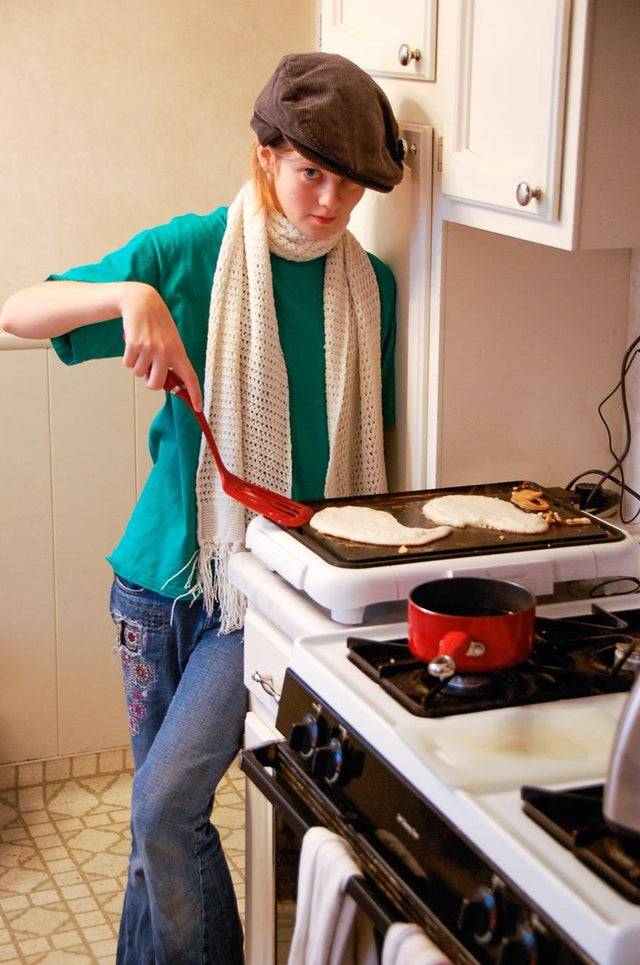 someone flipping pancakes in clothes that are weird and too big