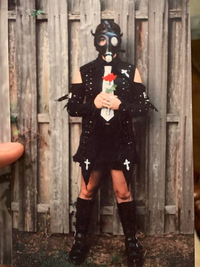 a guy holding a rose in a goth get up