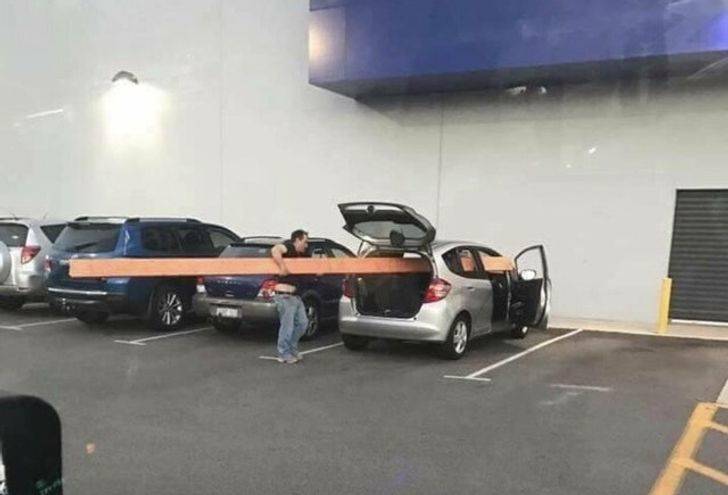 trying to fit a huge plank of wood into small car