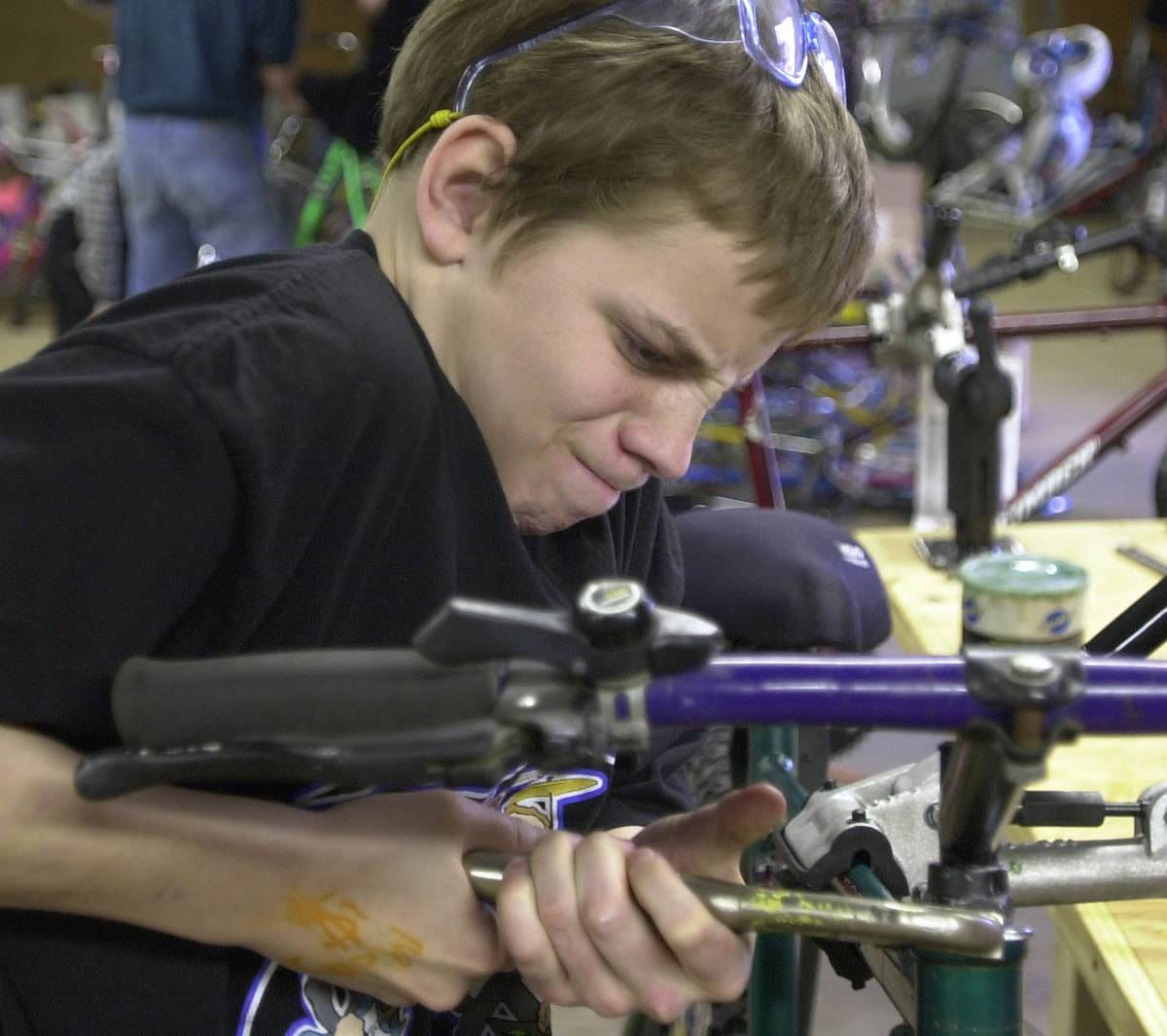 boy strains to lock a pair of vise-grips onto a headset nut while working on a bike