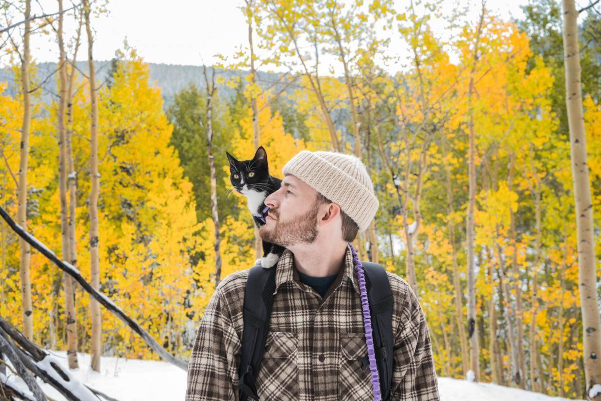 man with cat on shoulder outdoors in the winter