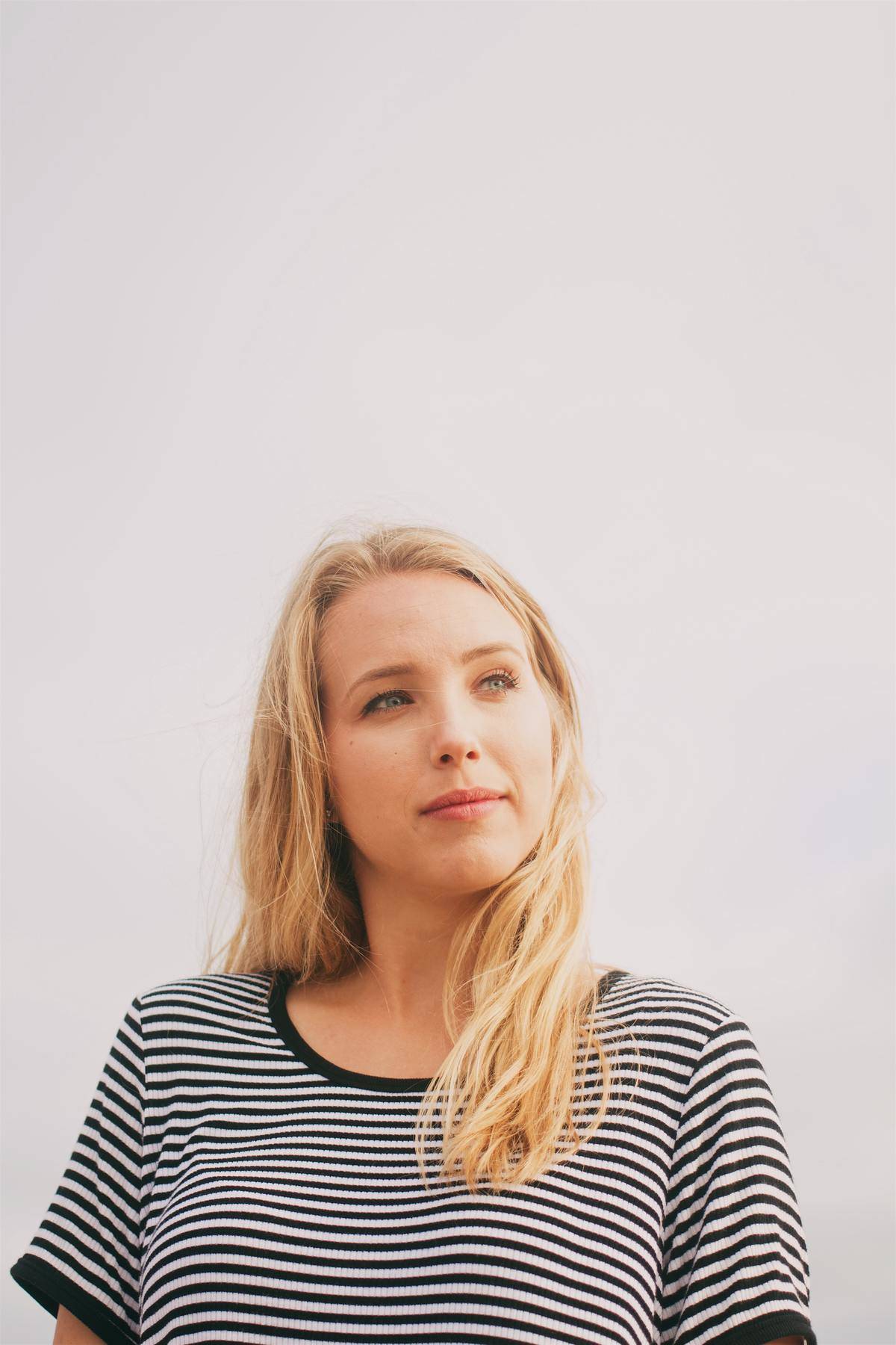 blonde woman looks off in the distance in striped shirt