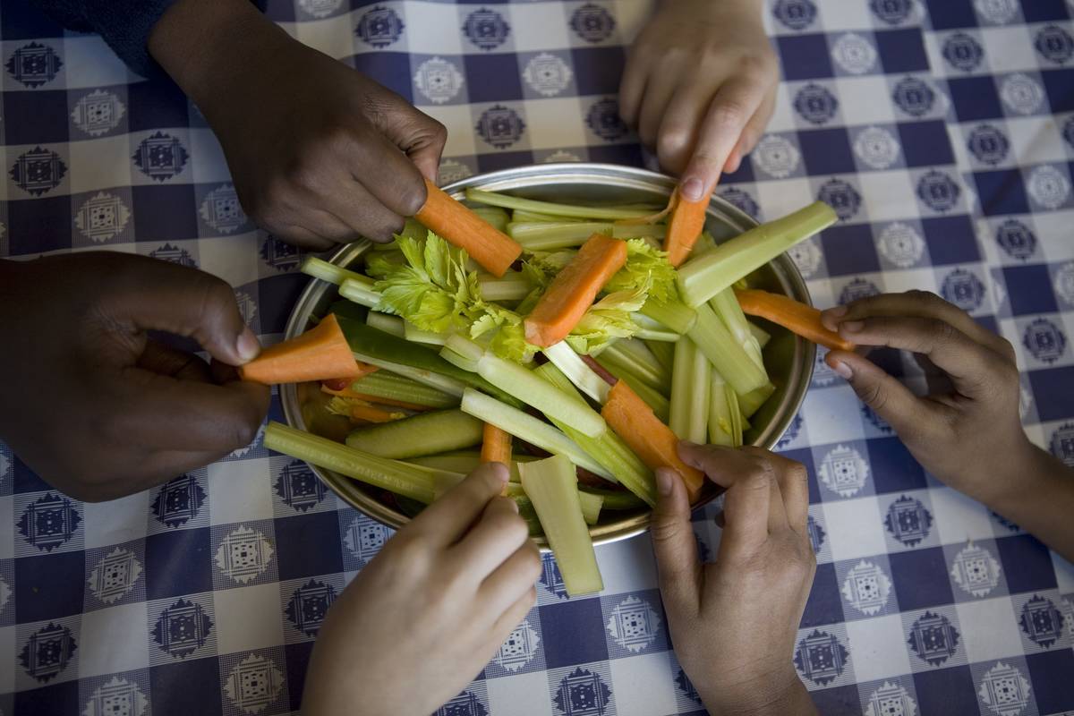 Students pull carrot and celery slices from a plate.