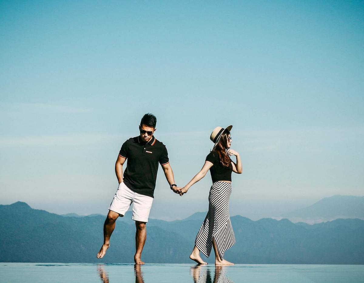 couple facing different directions pulling on hands
