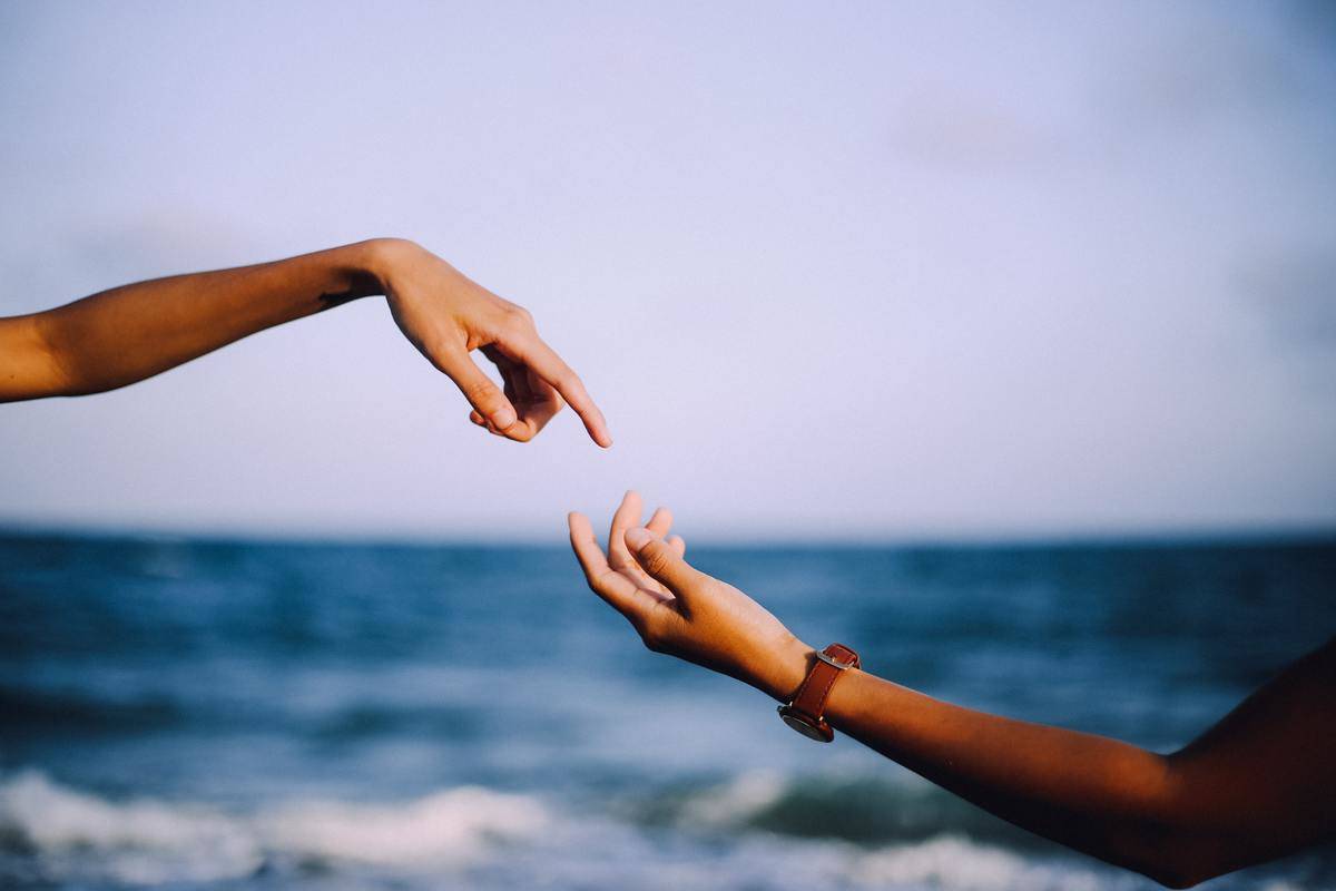two hands trying to touch at the beach