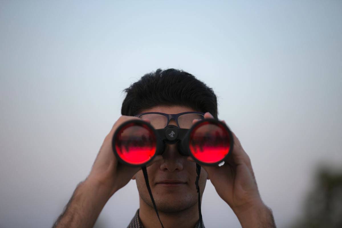 man looks through red glass binoculars