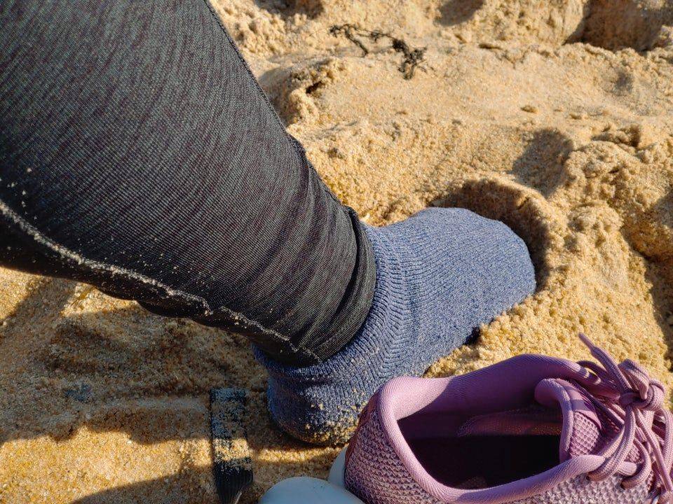 socked foot plunged in sand