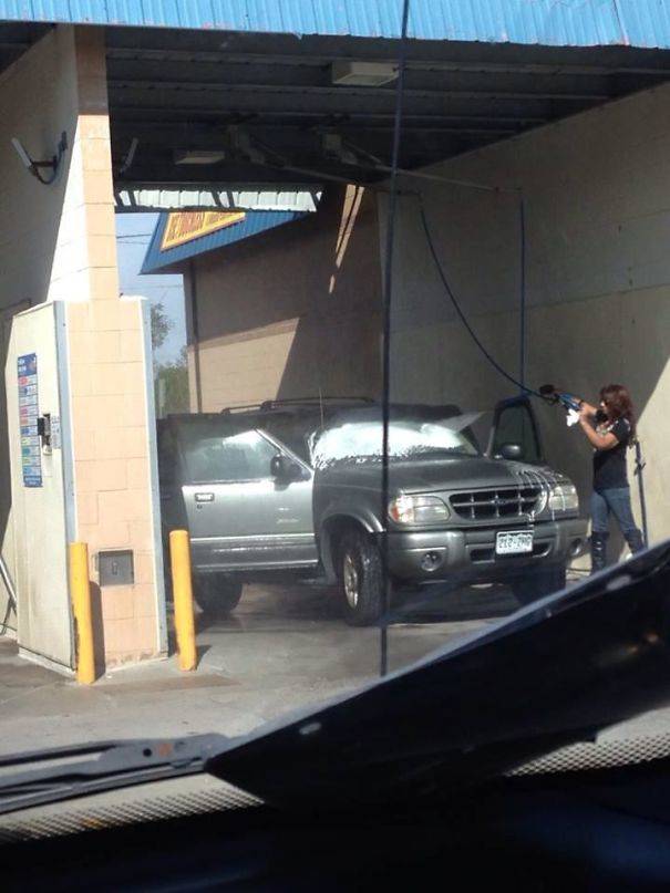 A person hosing down her SUV with the doors open.