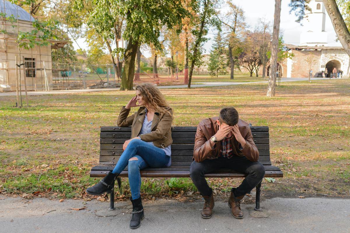 couple in fight while sitting on park bench