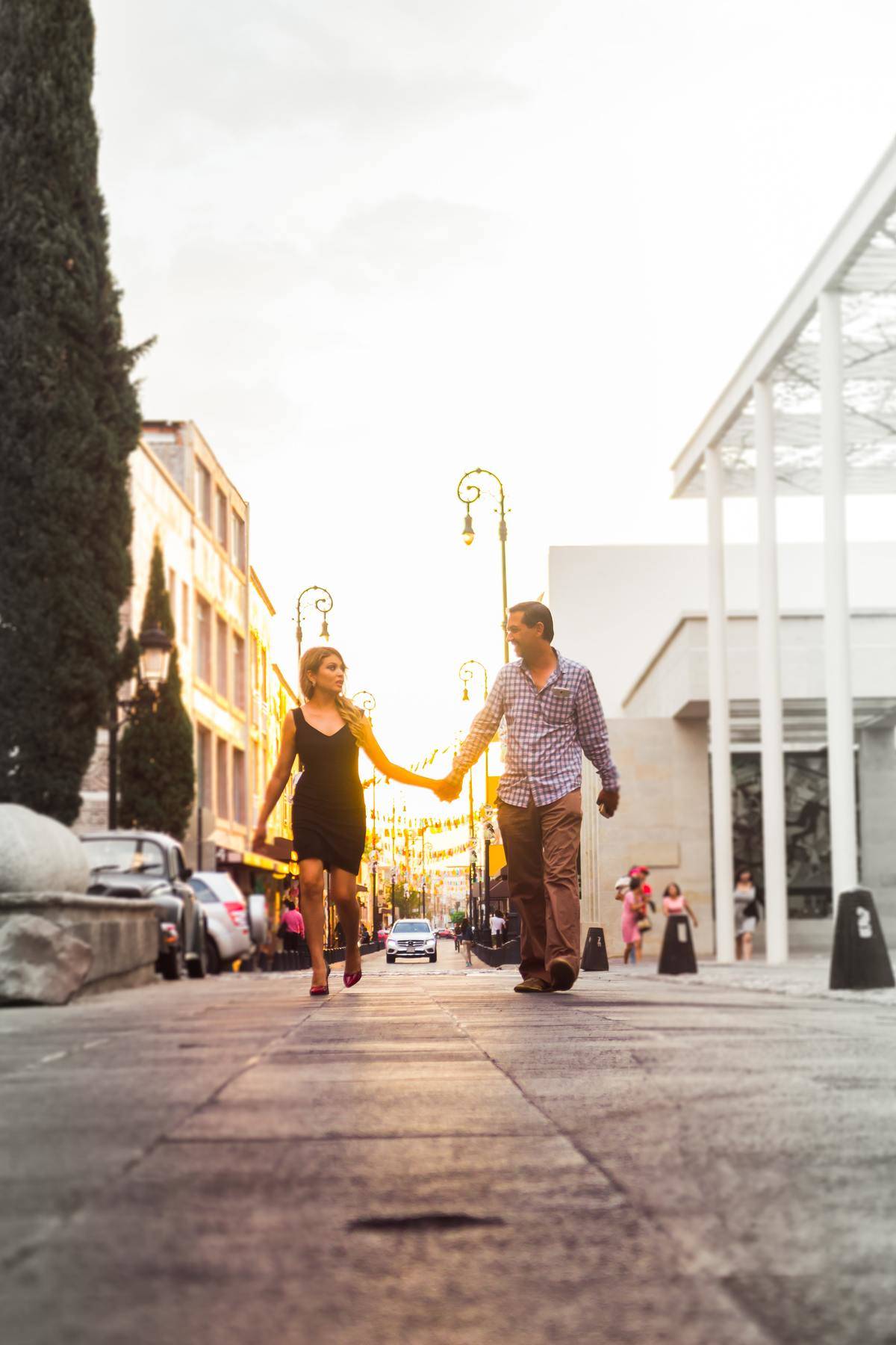 couple holding hands on street walking far apart