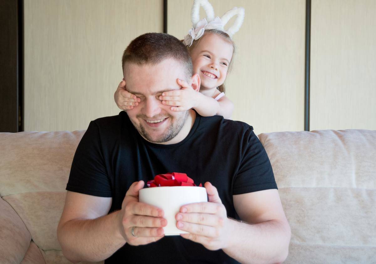 young girl covering dad's eyes