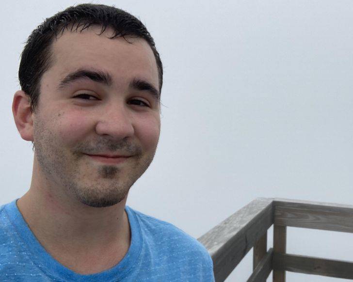 man takes selfie at very foggy lookout point where you can't see anything