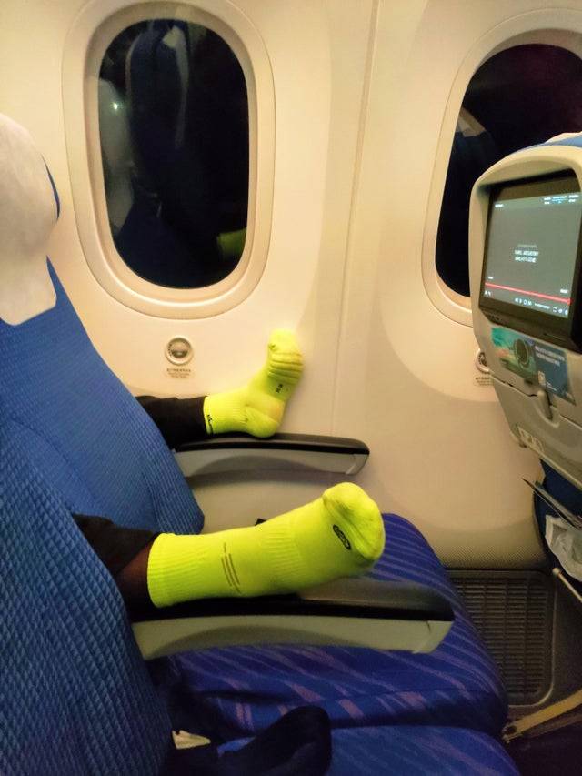 person puts feet on armrests of chair in front of him on plane