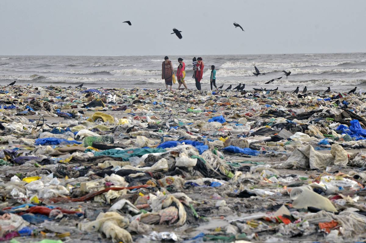 People walk across the trash-covered Juhu Beach in Mumbai, India.