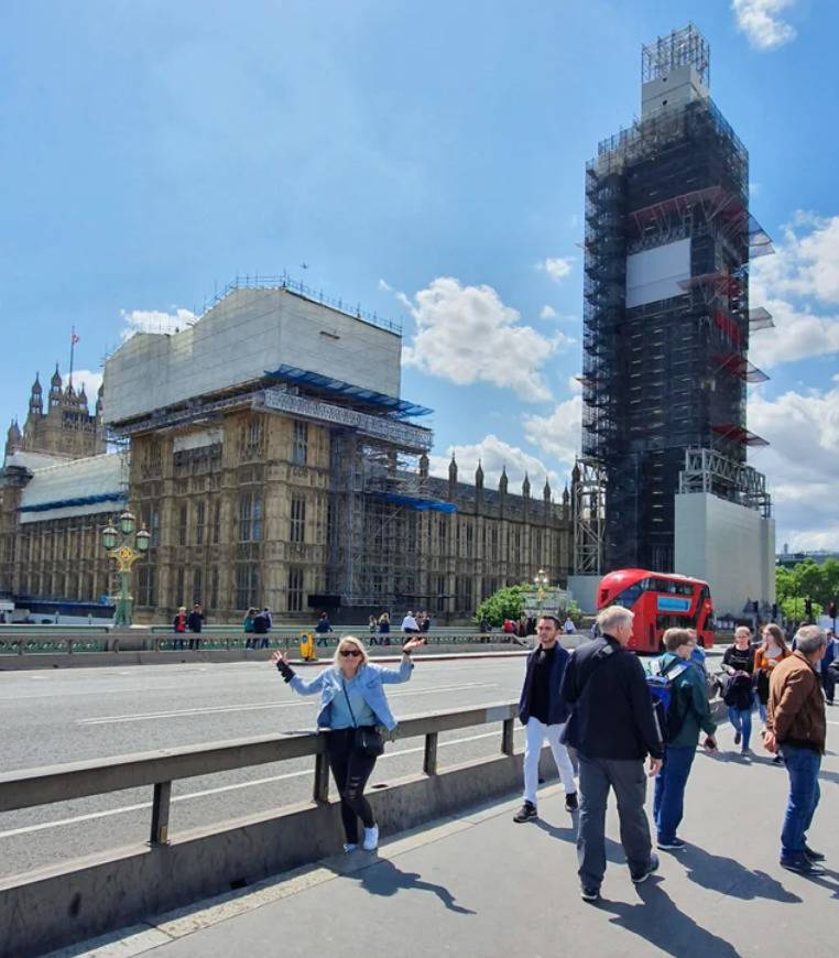 woman in London at Westminister Abbey with Big Ben encased in construction scaffolding