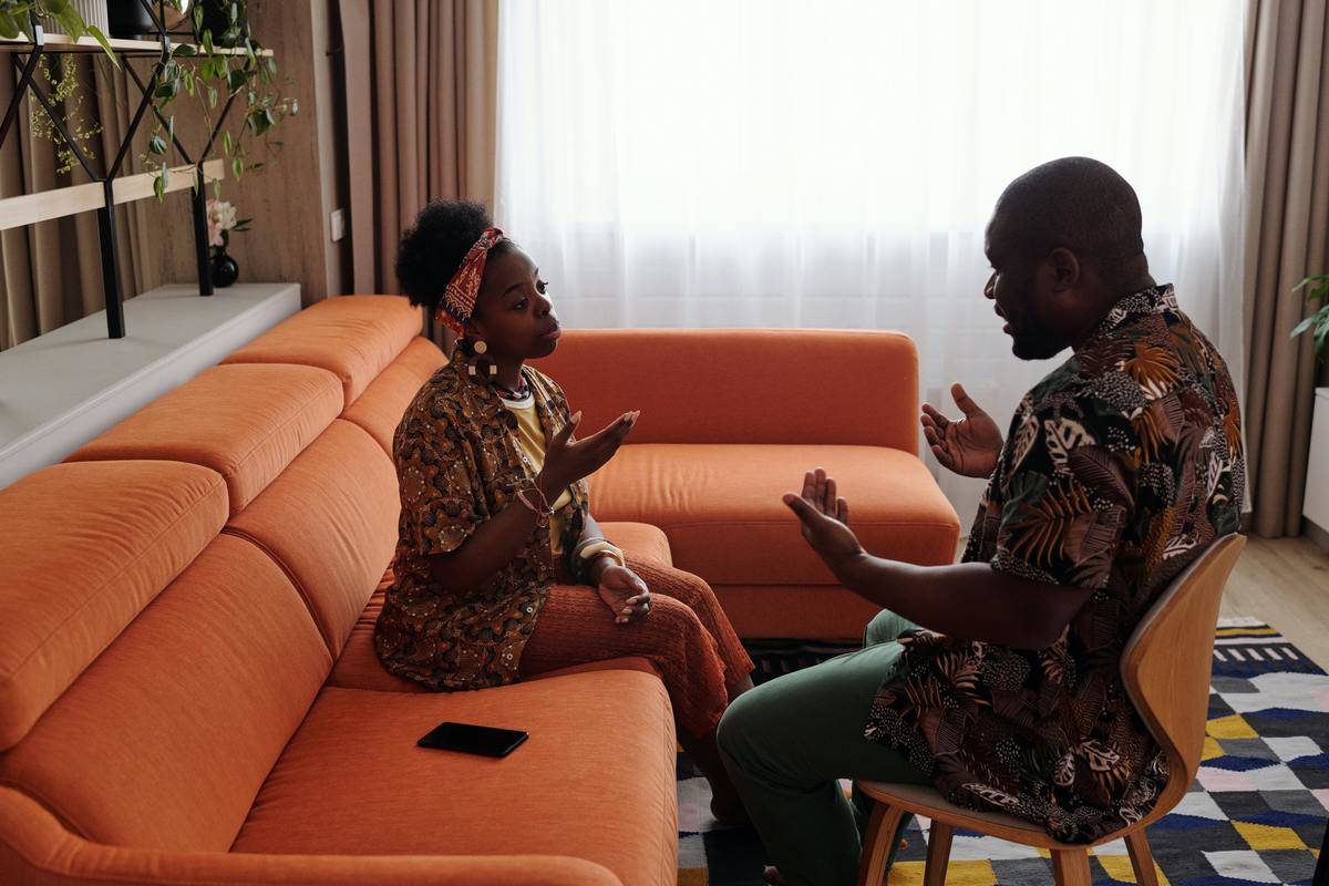 couple argues while sitting on an orange couch