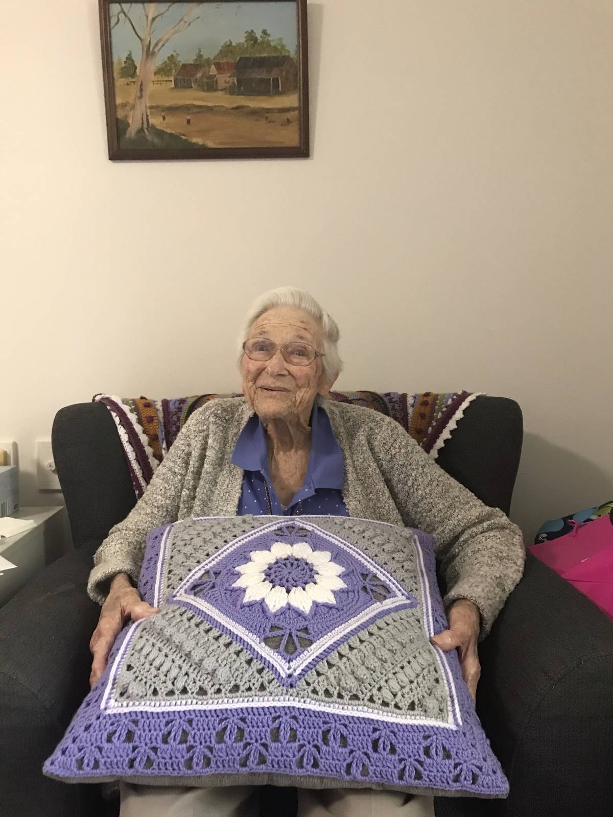 grandma holds crochet pillow and smiles