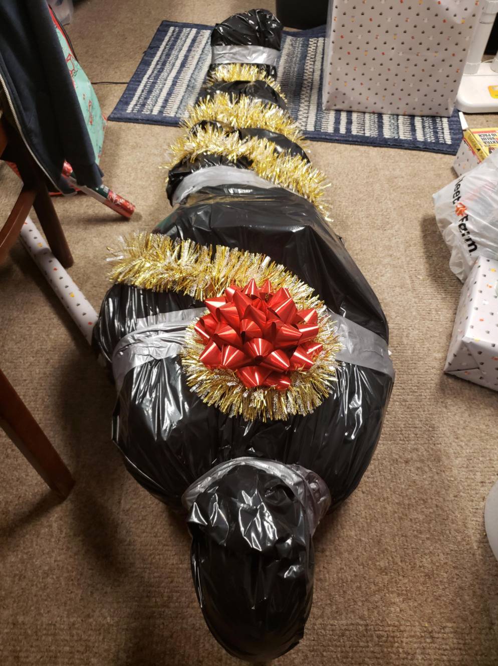 gift wrapped in garbage bags like dead body with bow on top