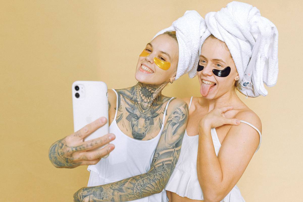 two girls doing eye masks taking a selfie 