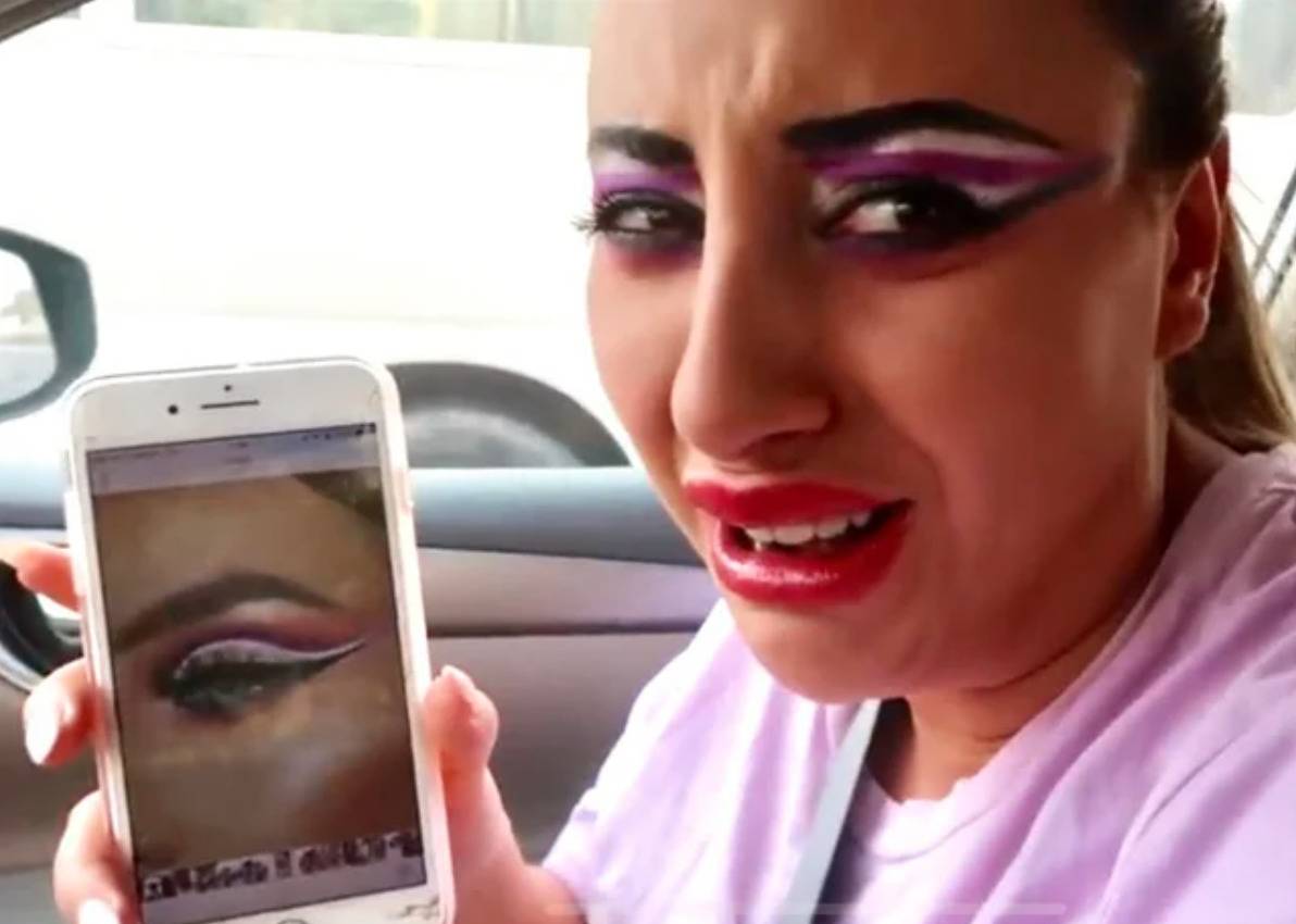 woman shows photo of what she asked for (purple cut crease) next to her face (horrible unblended disaster)