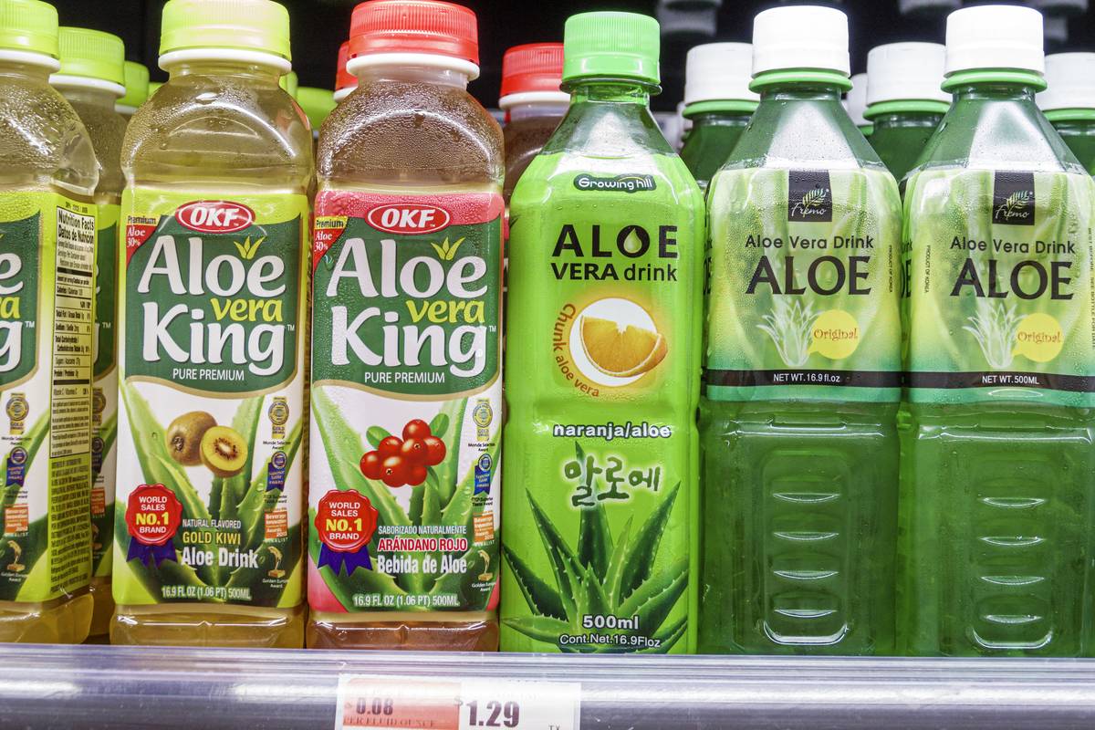Plastic bottles of aloe vera juice line the shelves of a market.