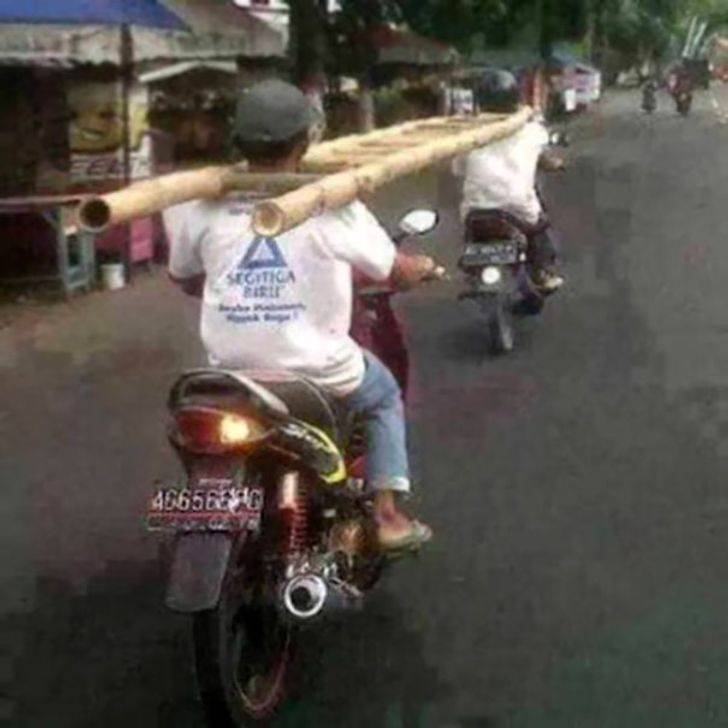men transporting ladder by having their heads between the rungs as they ride motorbikes