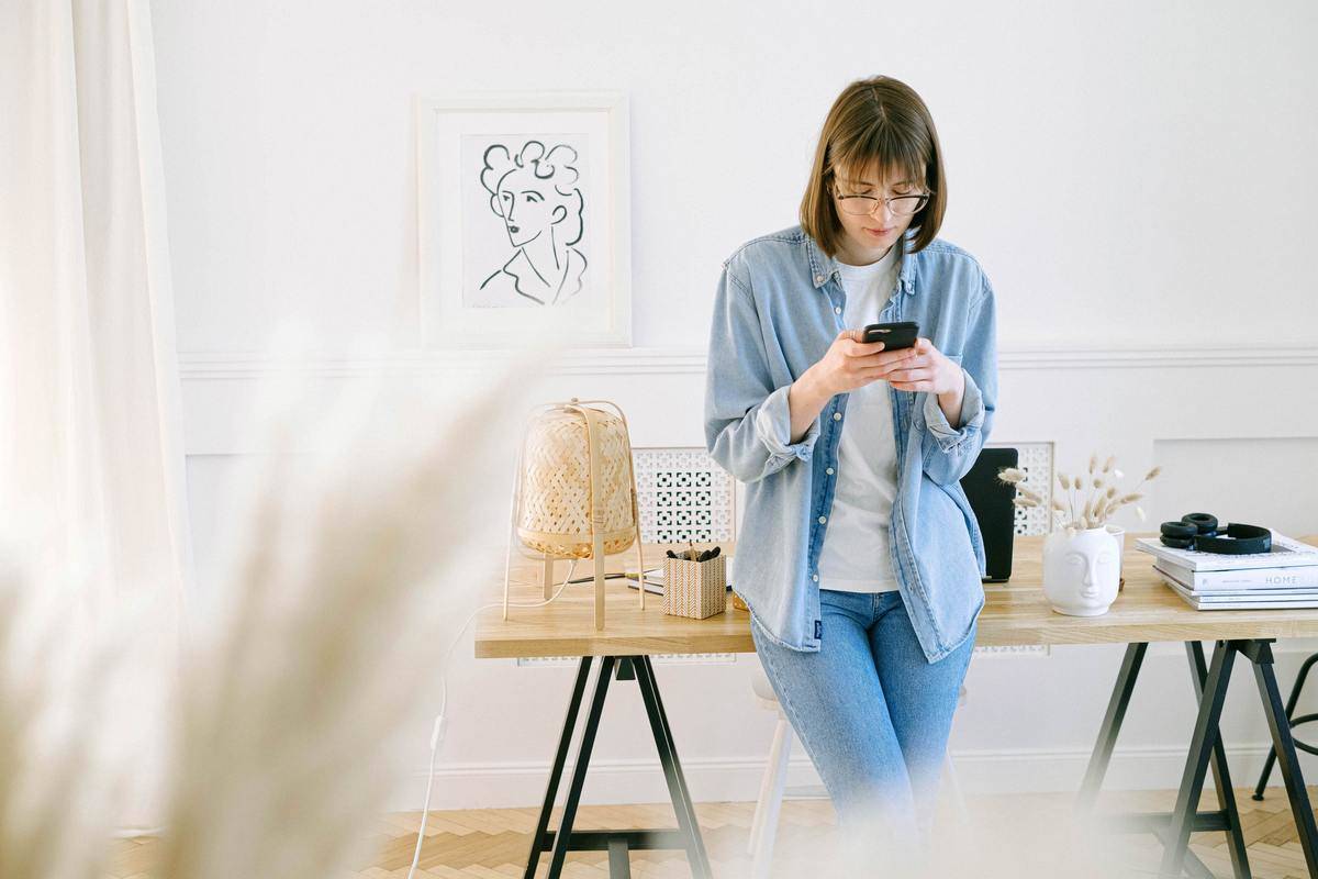 woman leaning on a desk looking down at her phone 