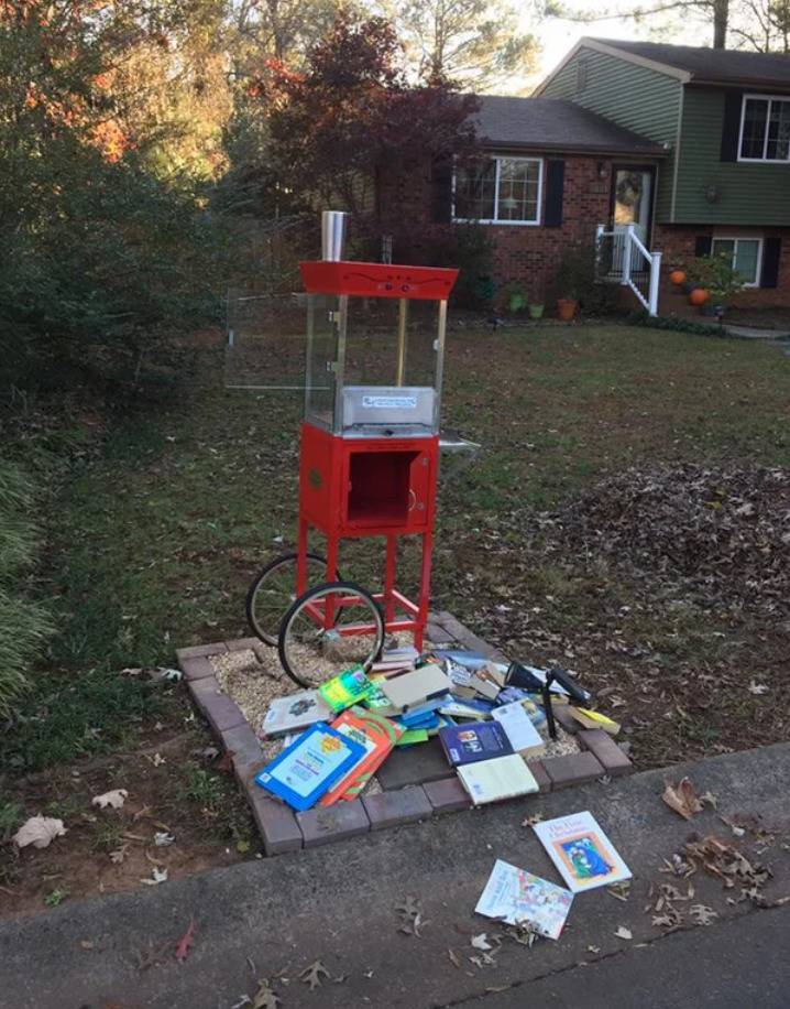 elevated box on front lawn with books scattered all across the ground