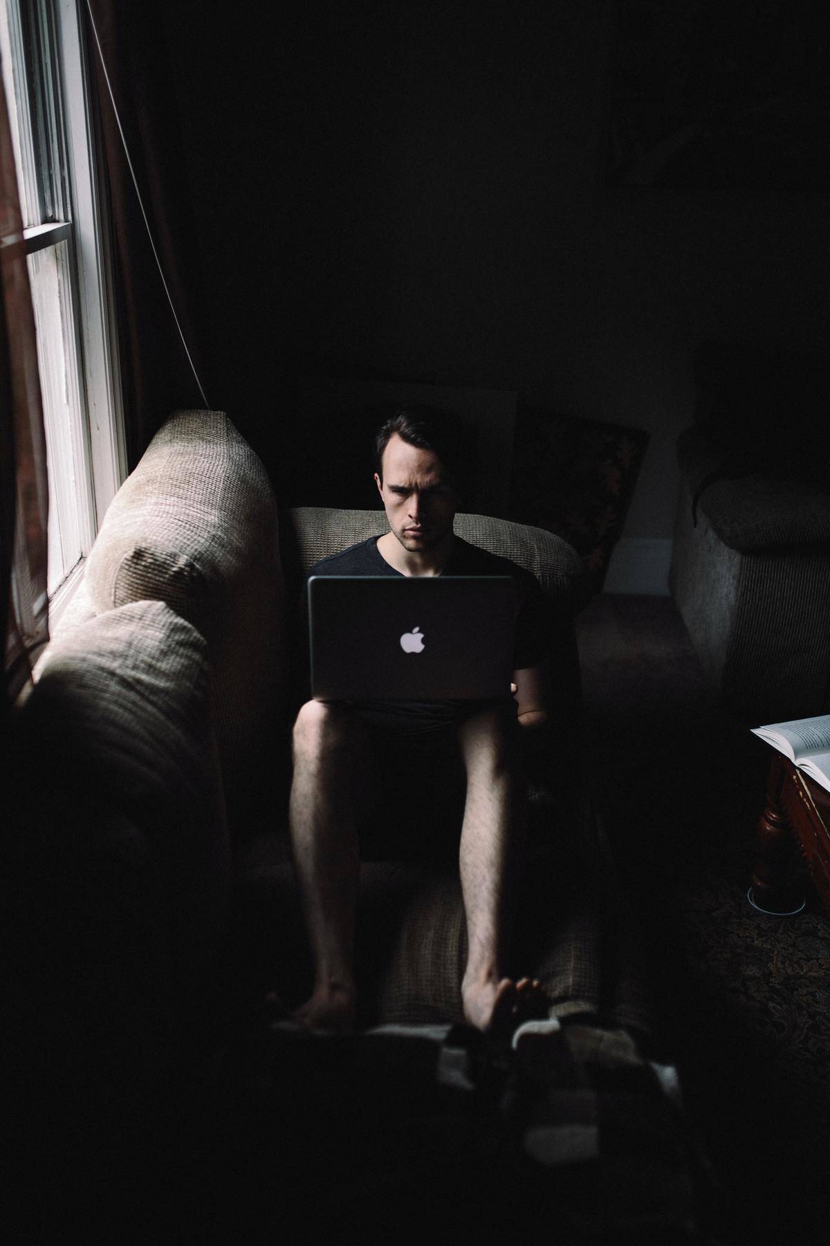 man sitting using laptop looking angry