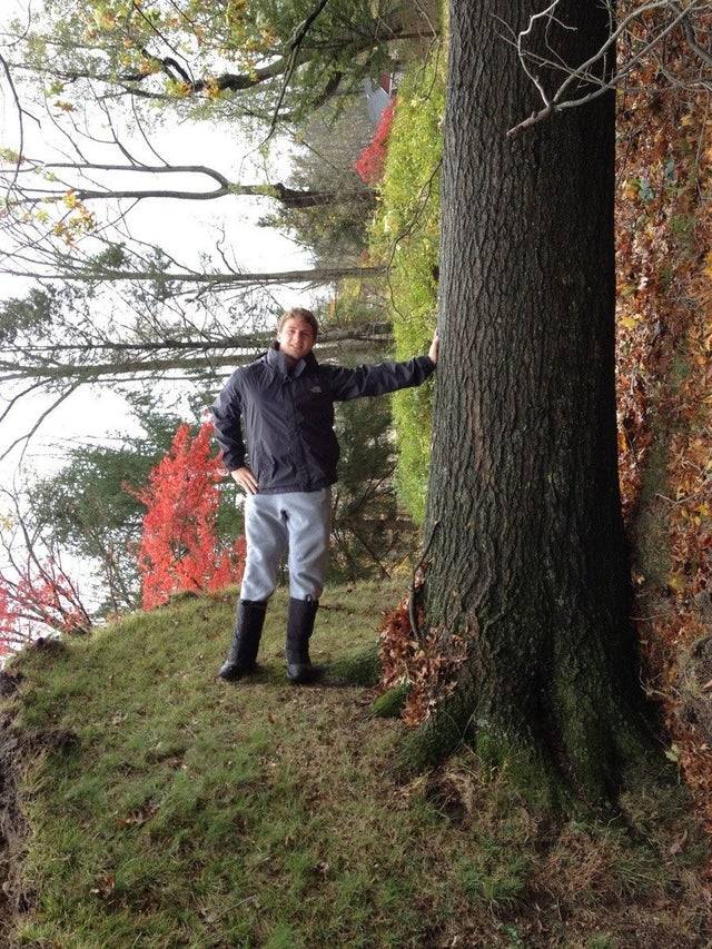 man leaning against fallen tree turned photo so it looks like he's standing