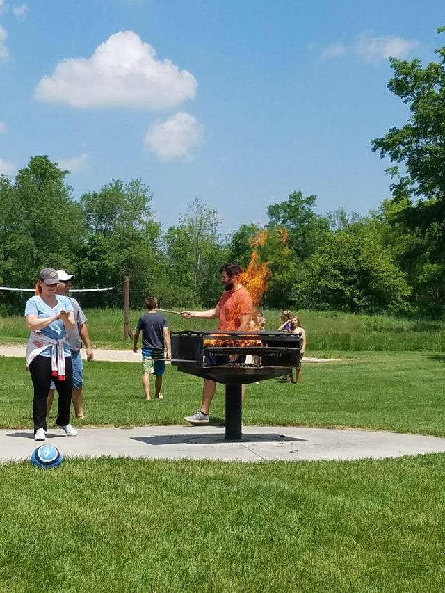 man walking behind fire pit who looks like he's lit on fire