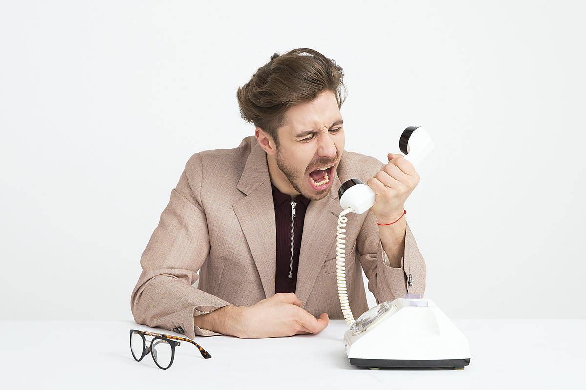 man yelling into the receiver of a phone