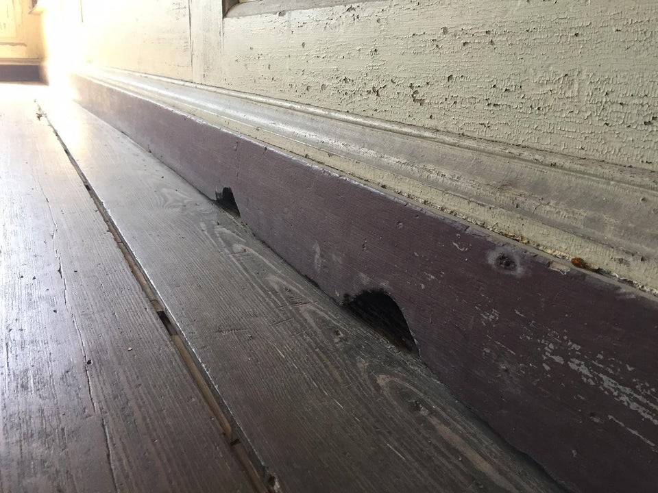 Two mouse holes are seen in the walls of an old home. 