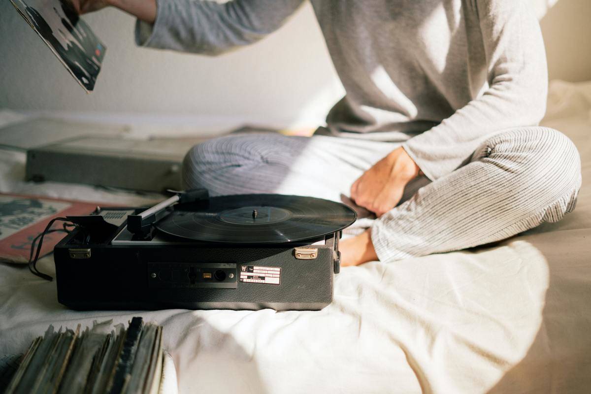 someone sitting on their bed listening to a record player
