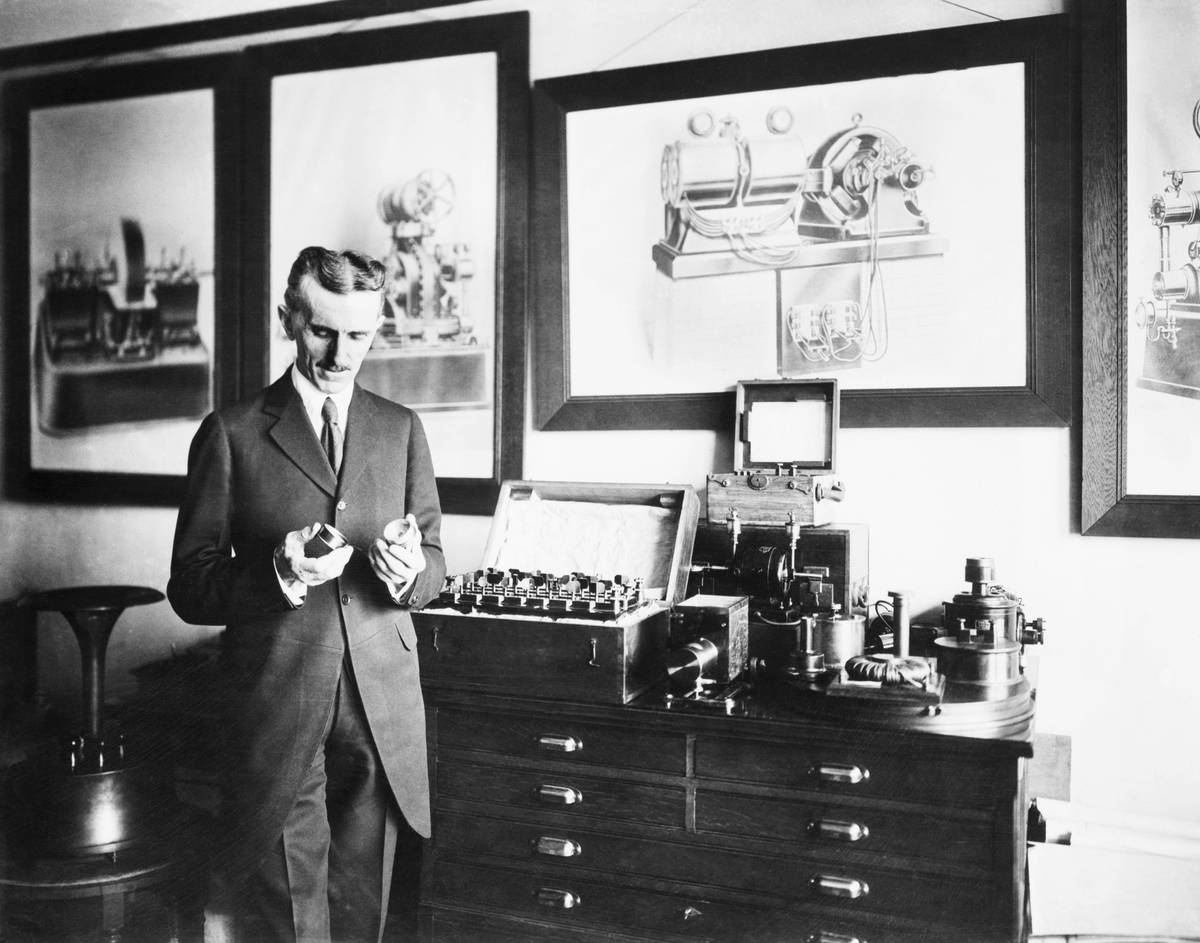 Nikola Tesla tinkers with a device in his laboratory.