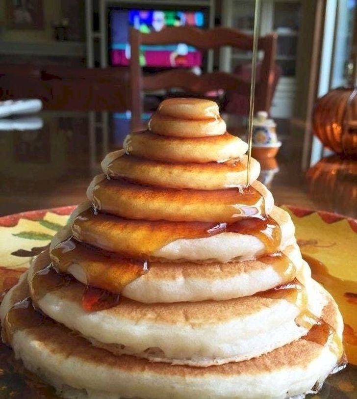 A stack of progressively smaller fluffy pancakes covered in syrup