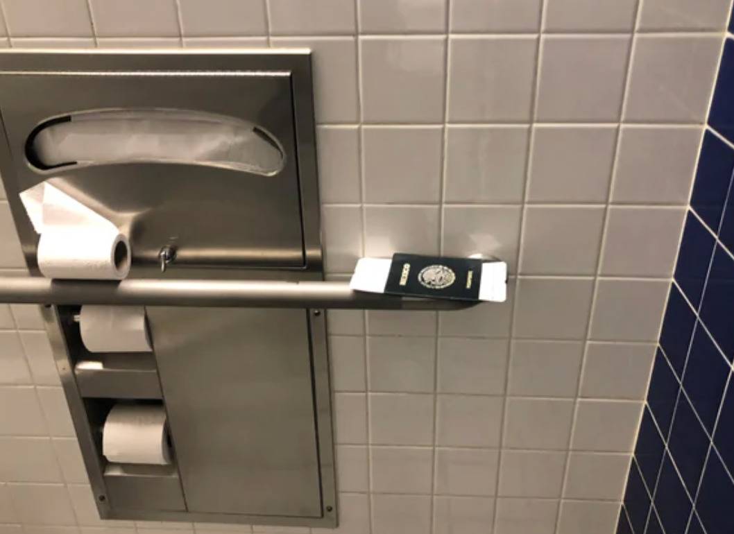 passport balancing on the handrail in a public bathroom