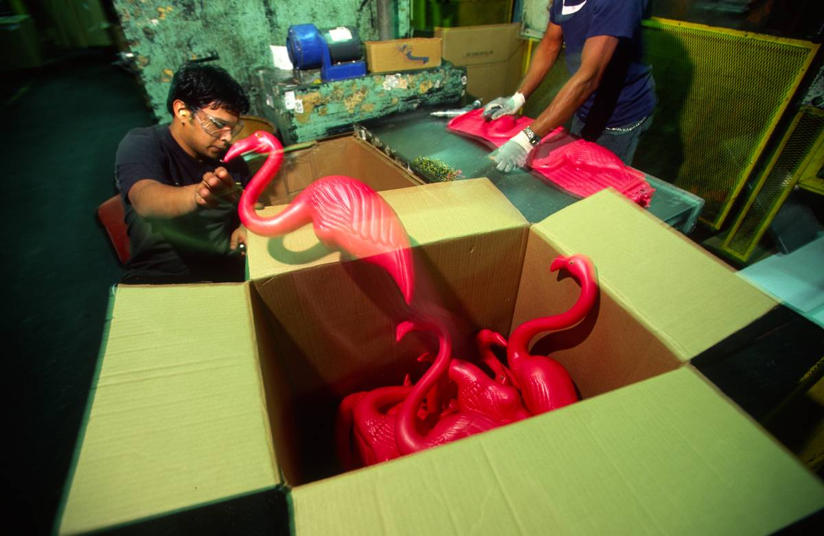 A plastic pink flamingo is handled by factory workers who file down the rough edges during the flamingo's production at Union Products on March 18, 2004 in Leominster, Massachusetts.