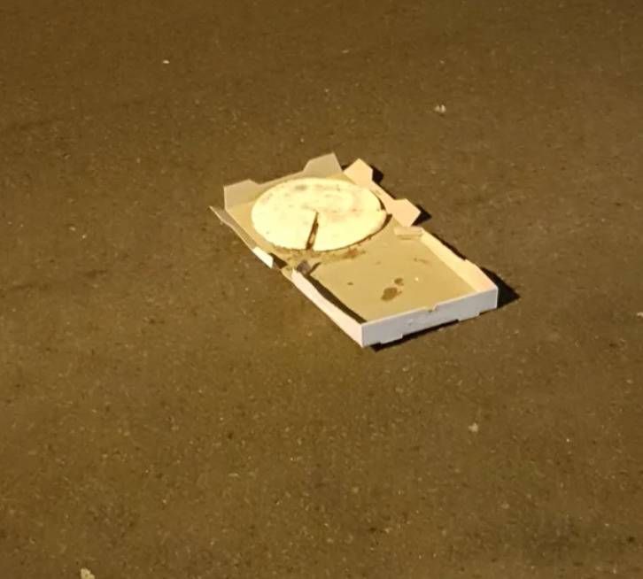upside down pizza in box on pavement