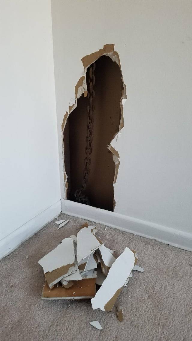 A hanging chain is seen inside of a wall.