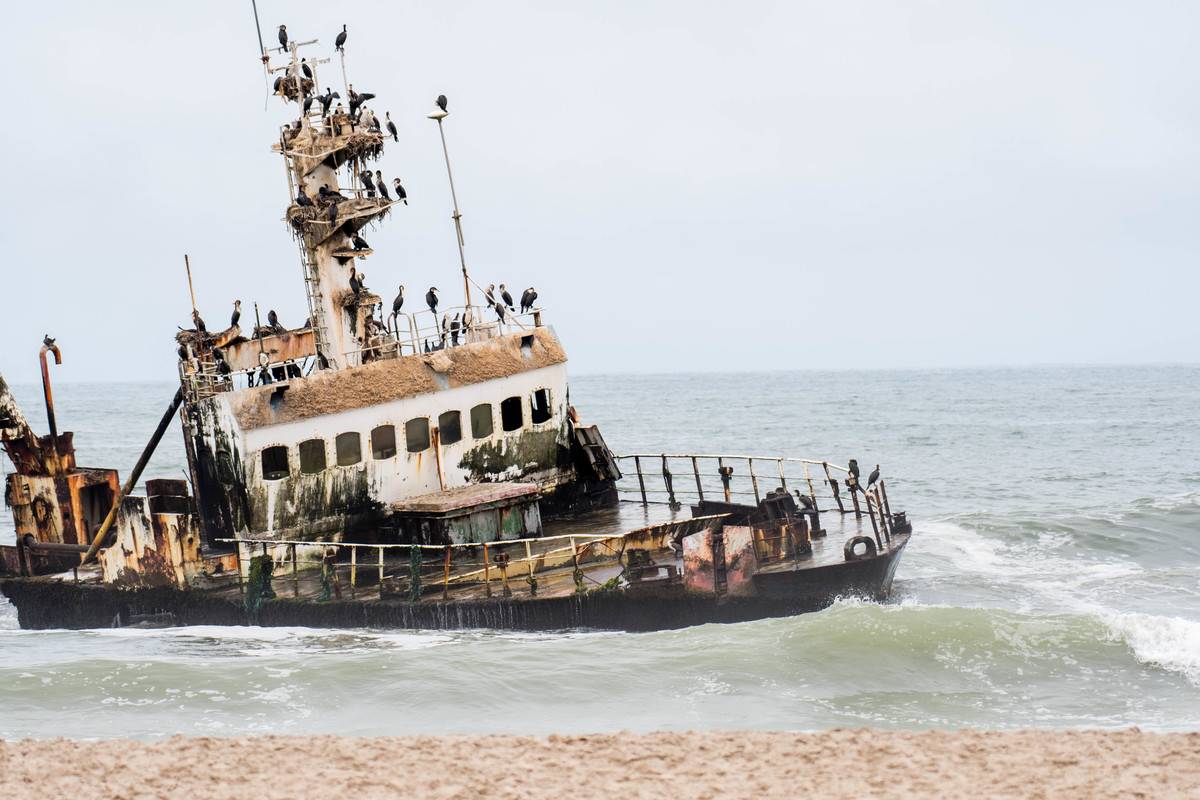 A shipwrecked ship appears on the coast of Skeleton Bay, Namibia.