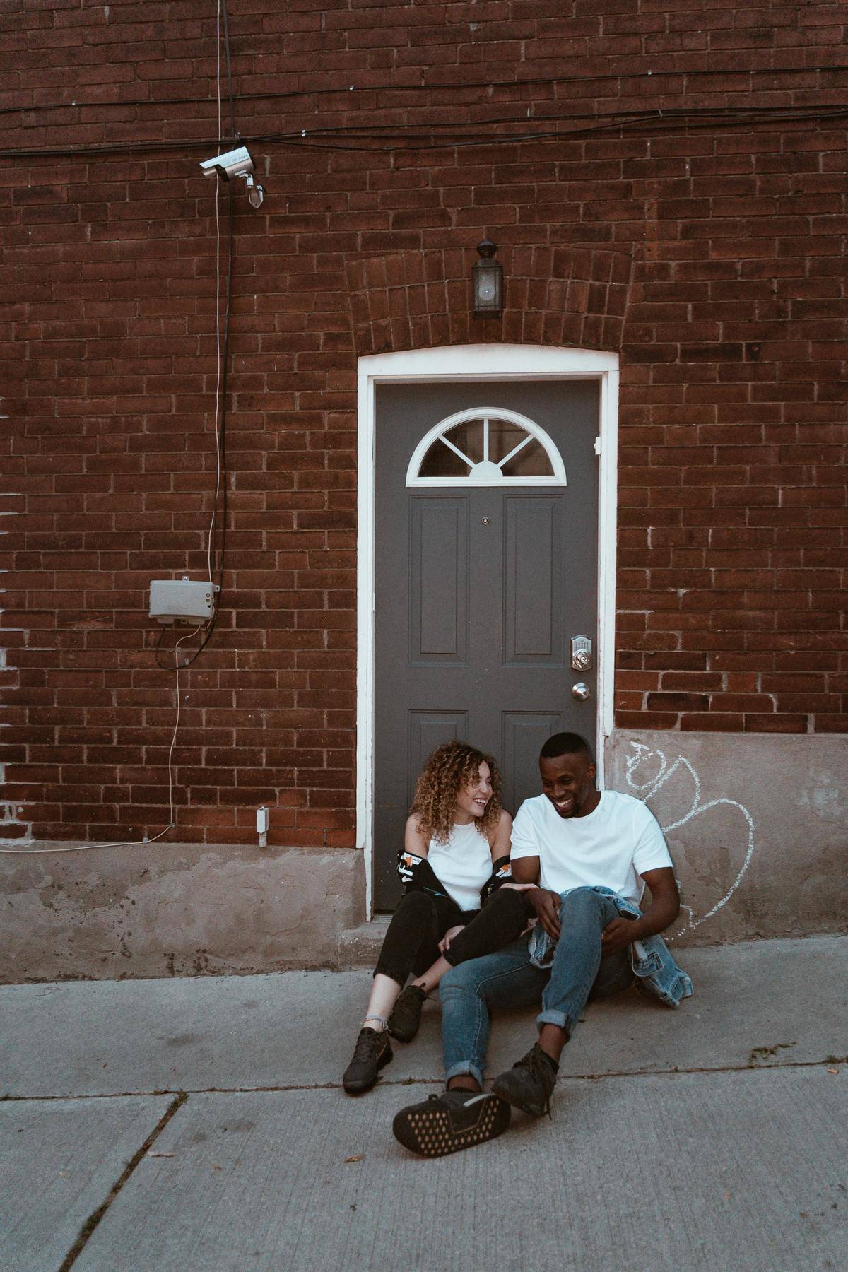 couple on a date sitting by a door laughing 